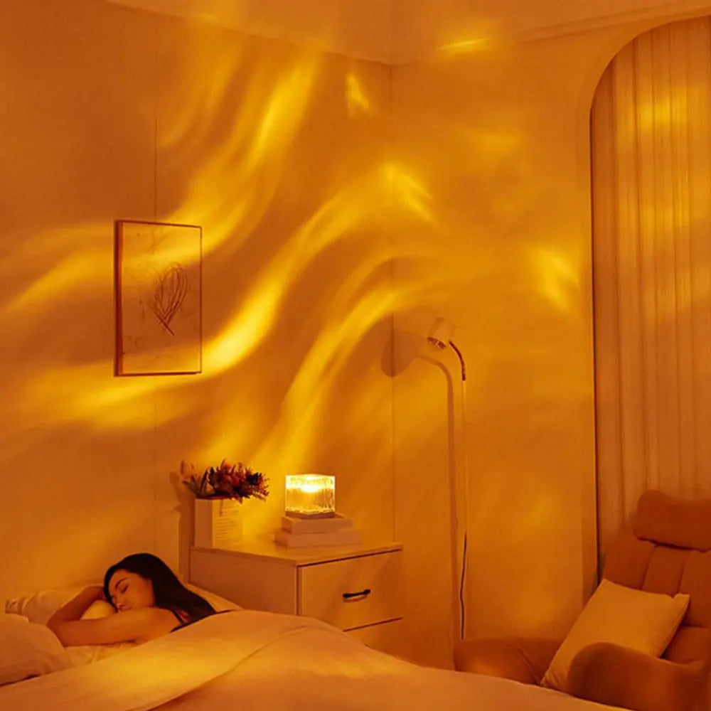 Warm ambient LED cube lamp with a wave-textured design, casting a soothing golden glow with flowing light patterns across the bedroom wall. Placed on a nightstand beside a sleeping woman, this lamp creates a calming, cozy atmosphere ideal for relaxation and sleep. Minimalist decor with neutral tones enhances the tranquil setting.