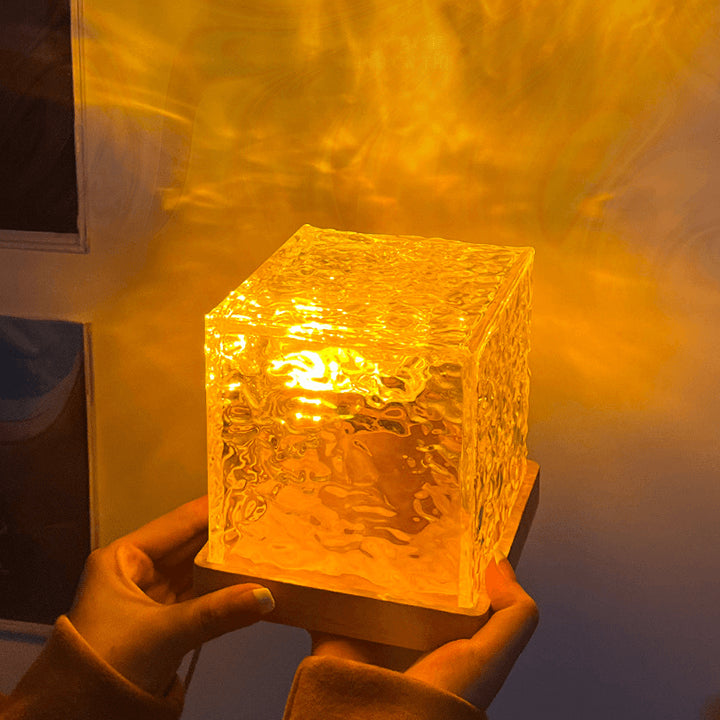 Warm ambient LED cube lamp with textured glass design held in hands. Unique lighting fixture emitting golden glow, ideal for cozy interior decor, mood lighting, and modern aesthetics. Perfect for creating a relaxing atmosphere in bedrooms, living rooms, or study spaces.