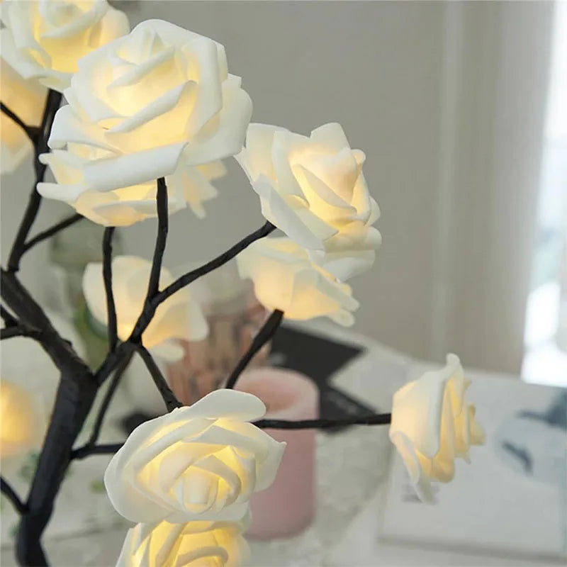 Close-up of glowing LED rose flower lights on a decorative tree lamp with warm yellow illumination, perfect for creating a cozy and romantic ambiance in home decor, featuring realistic rose petals on black branches