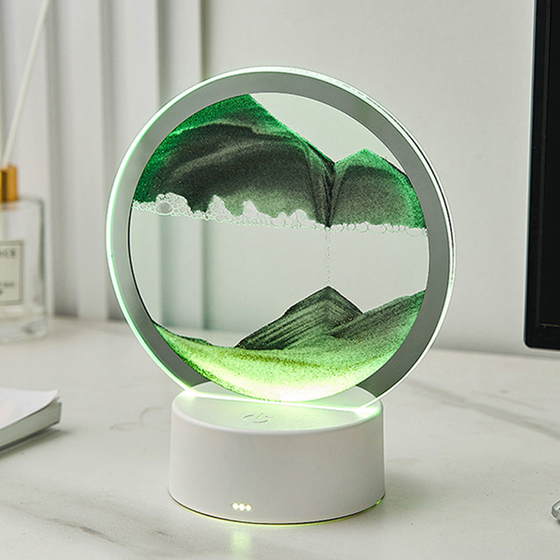 A circular LED sand art lamp with green sand, creating a calming mountain landscape effect. The ambient light enhances the sand's intricate patterns, making this lamp an elegant decorative addition to any desk or shelf.