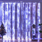 Elegant white LED curtain lights hanging over sheer curtains, creating a soft and serene ambiance in the room. The cascading lights bring a wintery, festive touch, perfect for holiday decor or adding a dreamy glow to any space. The setup includes a small decorated Christmas tree and a bookshelf with plants and decorative items, enhancing the cozy and welcoming atmosphere.