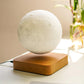 A levitating moon lamp with realistic lunar texture, suspended above a natural wood base. The lamp appears to float mid-air, providing a calming glow and adding an enchanting touch to any room. Perfect as a decorative piece or nightlight.