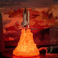 Space shuttle rocket lamp with vivid orange LED flame effect, capturing the look of a liftoff. The lamp, placed against a Mars-inspired background with warm red tones, creates a stunning, space-themed decor piece perfect for kids' rooms or space enthusiasts' displays. The lifelike flames add a unique glow, blending science fiction aesthetics with functional ambient lighting.