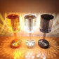 
Three ribbed crystal table lamps in warm amber, neutral white, and smoky gray tones, arranged side by side, casting a radiant and patterned light effect on the surrounding surface for a cozy and elegant ambiance.