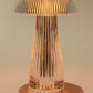 A close-up of a crystal mushroom LED lamp with a ribbed, transparent design. The lamp emits a warm, golden glow that accentuates its textured surface, creating an inviting ambient light. The mushroom shape, with its wide cap and slender stem, makes it a stylish and modern decorative piece, ideal for enhancing cozy indoor spaces. The warm light radiates through the crystal structure, casting soft reflections and shadows.
