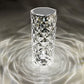 A crystal LED lamp with a tall, diamond-cut design, casting mesmerizing light patterns in concentric circles around it. The faceted surface of the lamp reflects light beautifully, creating a sophisticated ambiance with an almost water-like ripple effect. This elegant, modern lamp adds a touch of luxury and visual interest to any space, enhancing the room's decor with its unique and eye-catching lighting.






