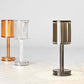 Three crystal table lamps in amber, clear, and smoked shades, each casting a unique light pattern on the surface. The ribbed design and minimalist structure of these lamps add a sophisticated, contemporary aesthetic to any space.