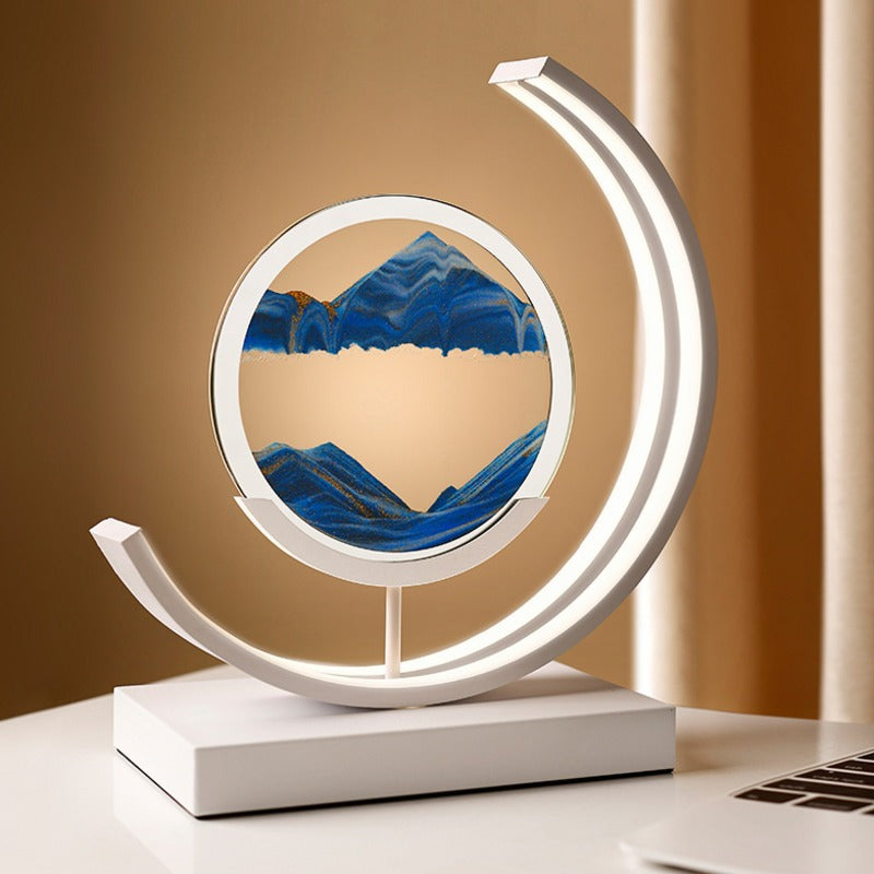 A crescent-shaped LED sand art lamp with a rotating sandscape in deep blue tones, designed for relaxation and aesthetic appeal. Perfect for adding a modern, calming element to any desk or tabletop.